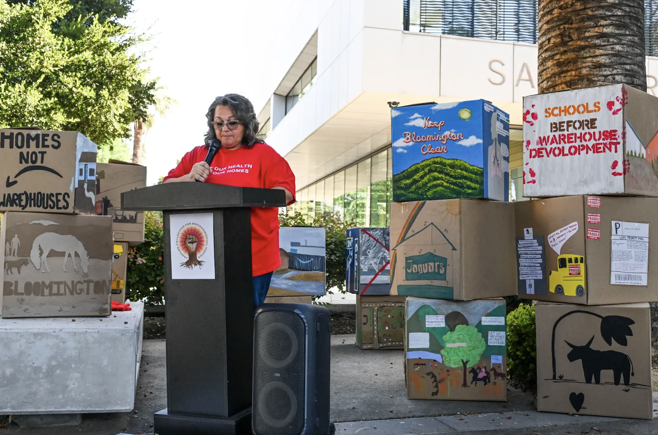 Community members speaking at a public hearing with protest signs